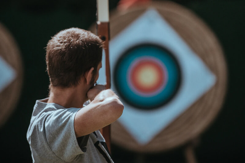 A man aiming a bow and arrow at a far away target.