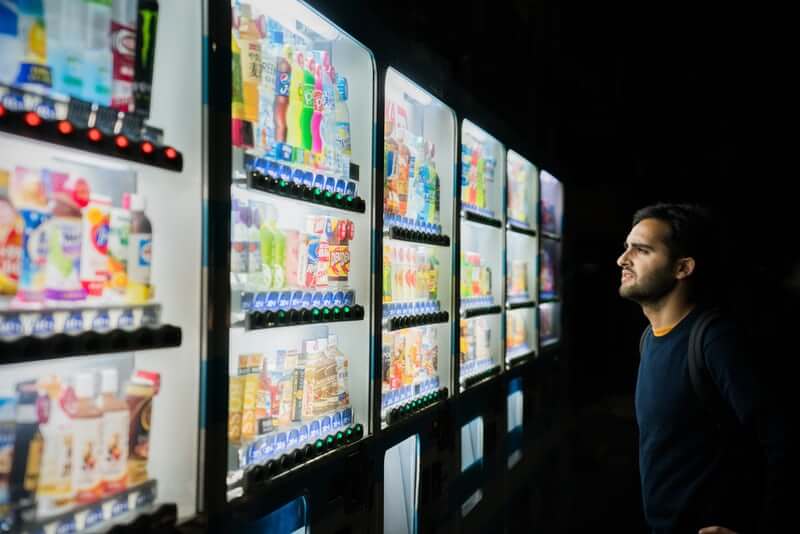 Man looking at vending machine with many options.